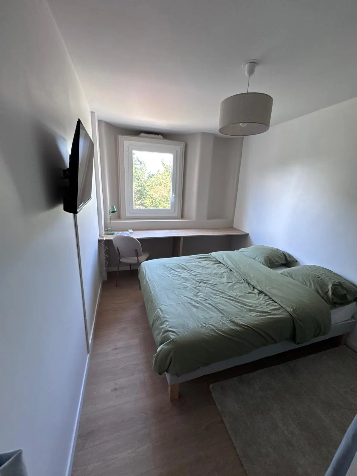 Grande chambre avec lit, télévision et bureau après rénovation à Noisy-le-Sec